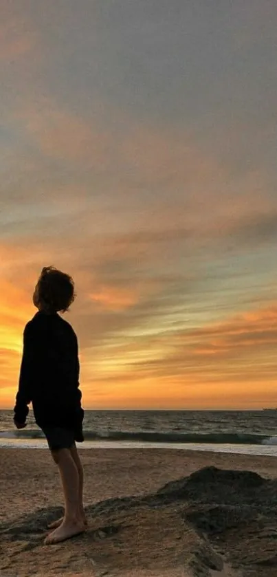 Silhouette at sunset on a beach with vibrant sky.