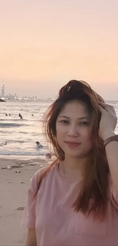 Woman enjoying a serene beach during a pink sunset.