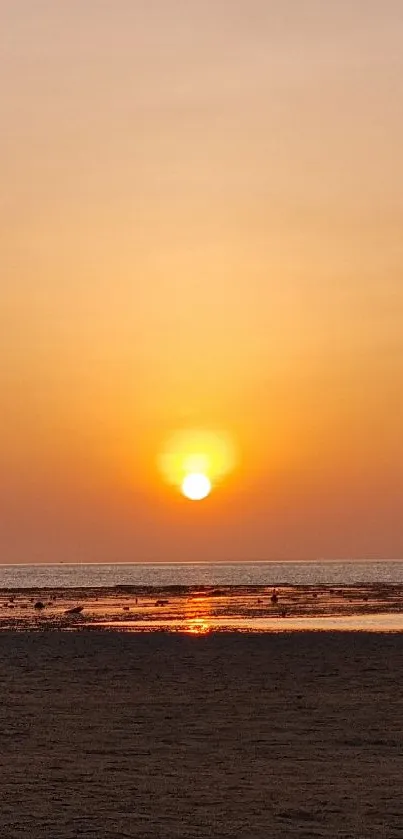 Serene sunset over ocean with orange skies.