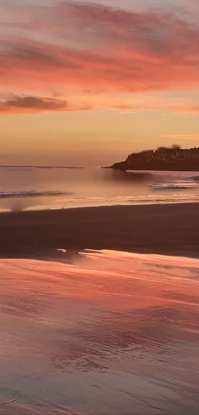 Serene beach at sunset with pink skies reflecting on calm water.