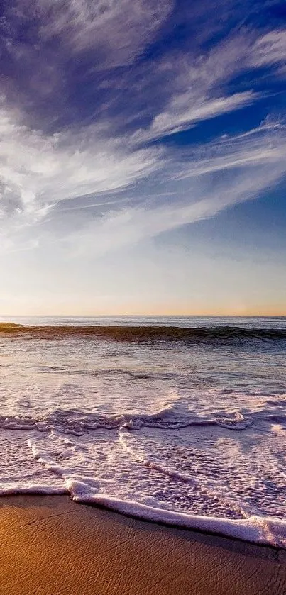 Sunset on beach with waves and blue sky.