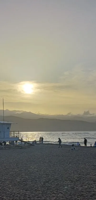 Serene sunset on a sandy beach with ocean waves and distant mountains.