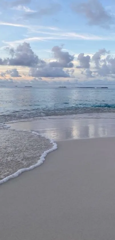 Serene sunset beach with waves gently lapping the shore under a sky-blue horizon.