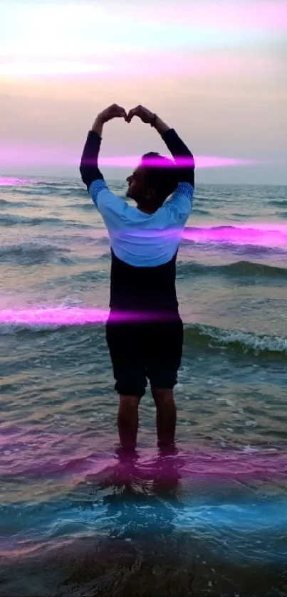 Person forming heart shape at beach during sunset.