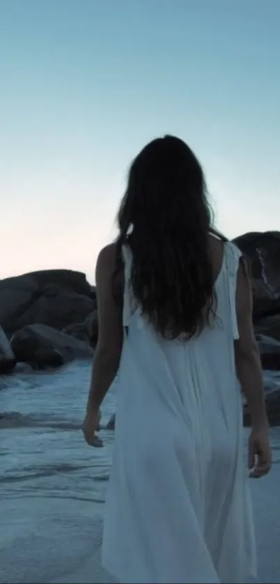 Woman walking on a serene beach at dusk.