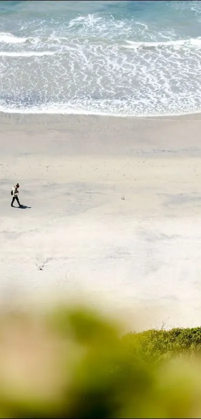 A person walking along a tranquil beach with waves in the distance.