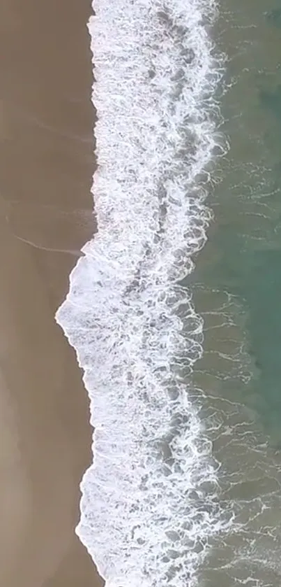 Aerial view of gentle beach waves meeting sandy shore, perfect for mobile wallpaper.