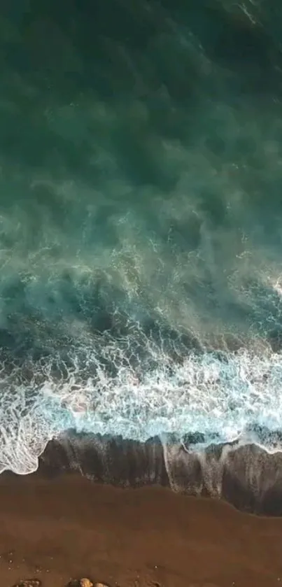 Top view of tranquil beach waves meeting the shore, showcasing serene oceanic hues.