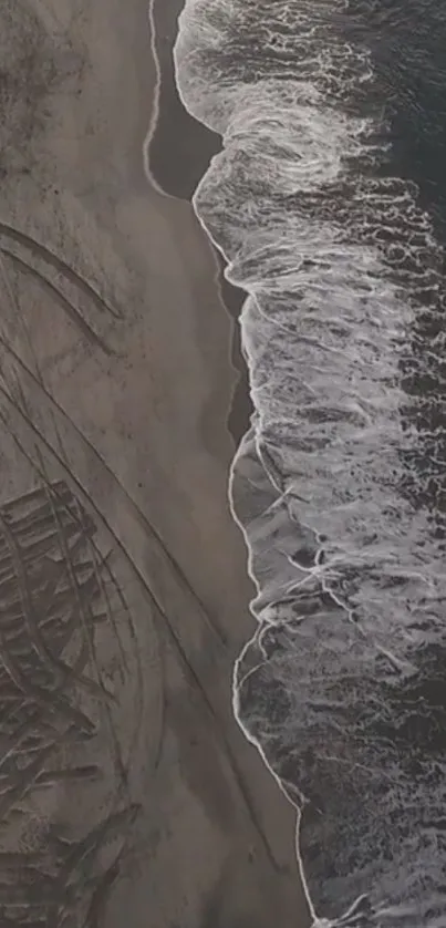 Aerial view of waves meeting sandy beach with textured patterns.