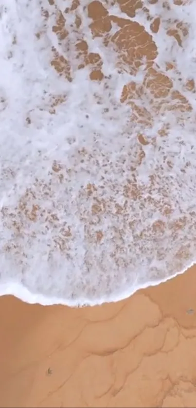 Aerial view of waves gently crashing on sandy beach.