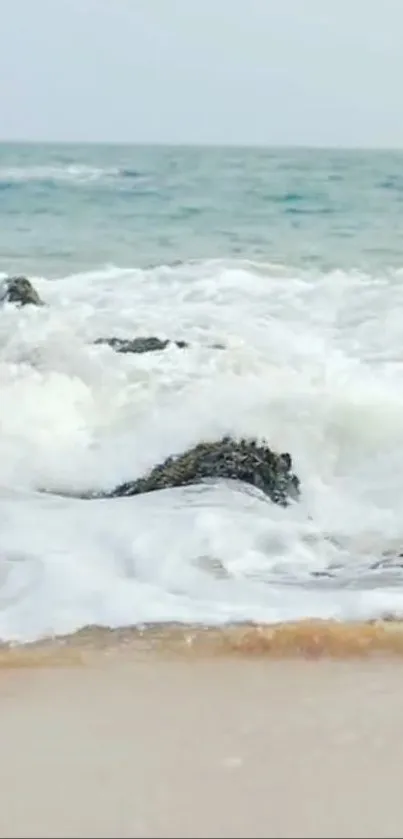 Peaceful beach with foamy waves crashing on rocks and sand.