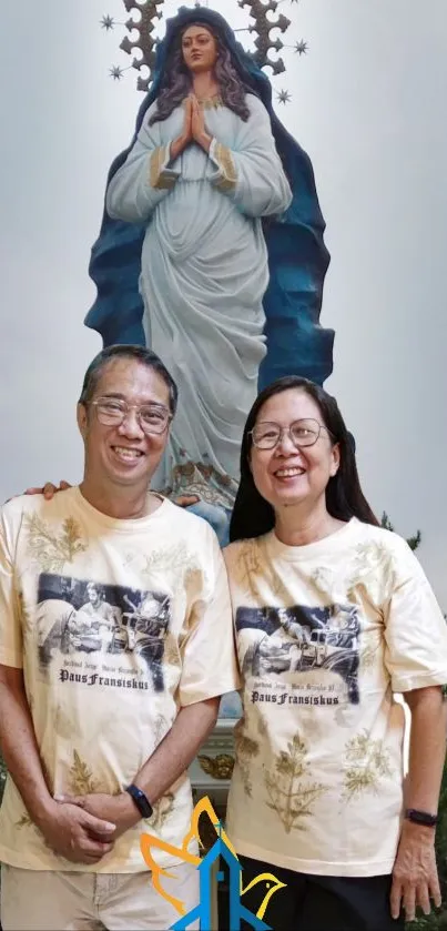 Couple standing before Virgin Mary statue in serene mobile wallpaper.