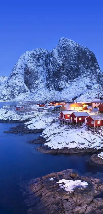 Snowy Arctic mountains with red cabins and blue sky.