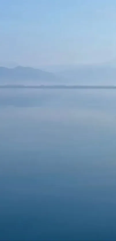 Serene blue lake with misty mountains.