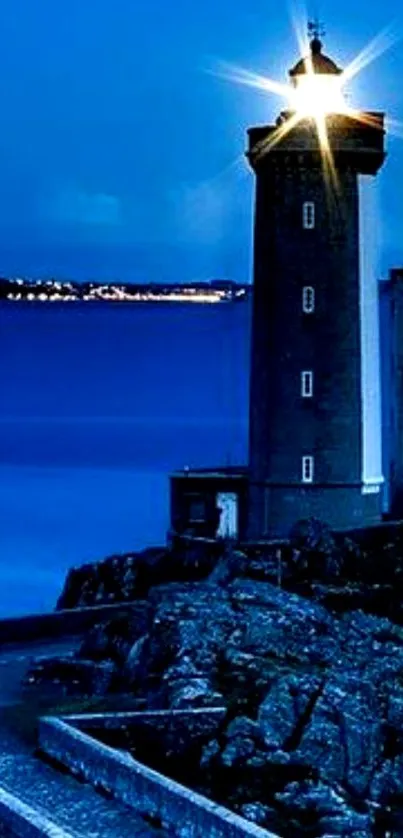 Serene blue lighthouse overlooking the ocean at night.