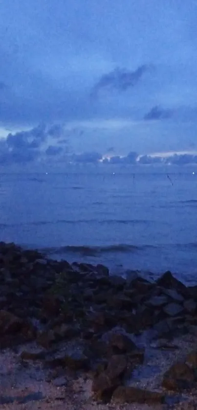 Serene twilight view over the ocean with calm waves and a blue sky.