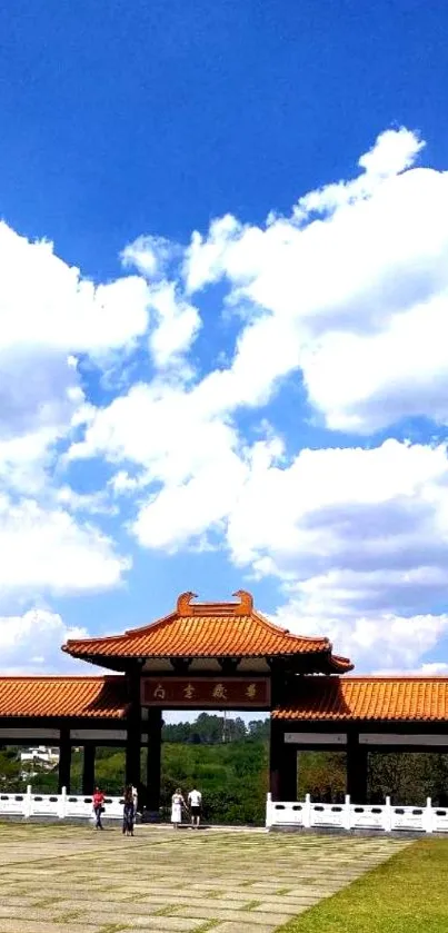 Serene blue sky and traditional gate wallpaper with fluffy clouds.