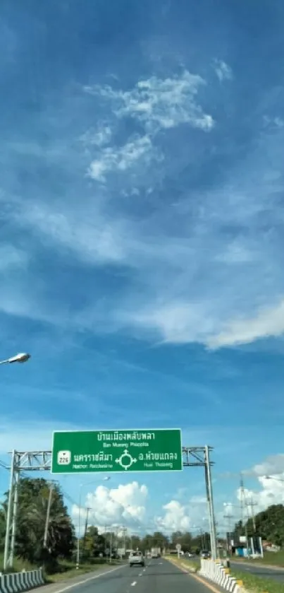 Road beneath a vibrant blue sky with white clouds and green scenery.