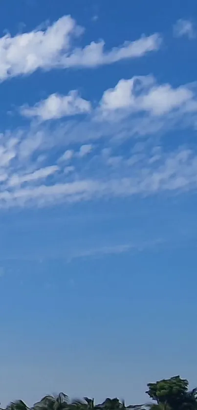 Peaceful blue sky with fluffy white clouds over green landscape.