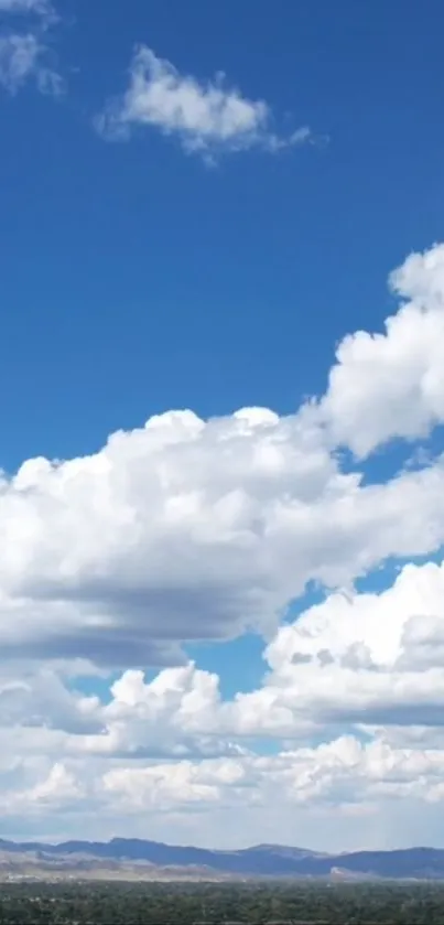 Serene sky with fluffy white clouds above a distant mountain range.