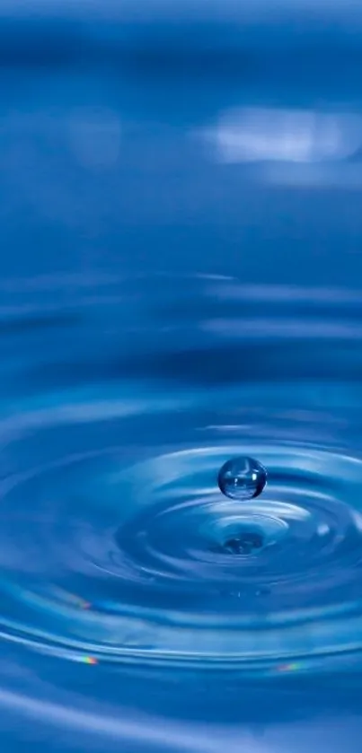 Close-up of a blue water ripple with a droplet above the surface.