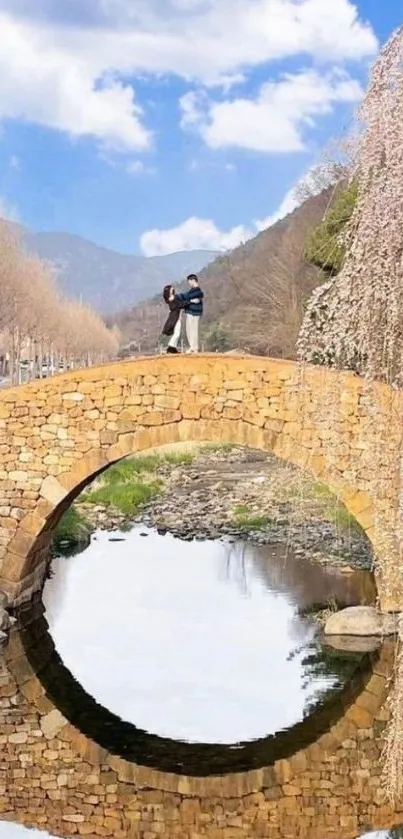 Stone bridge over a calm reflective river under a bright blue sky.