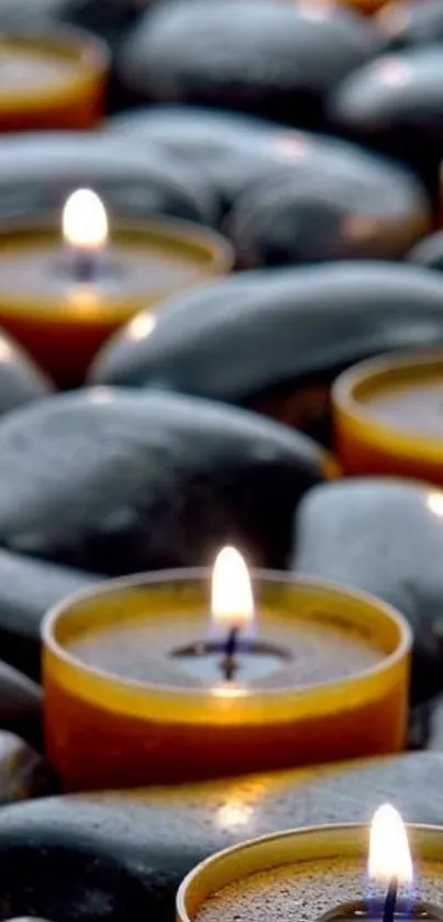 Serene image of candles on smooth stones for a calming mobile wallpaper.