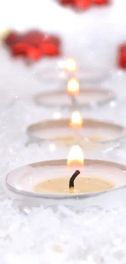 A serene row of candles on a snowy surface with festive red decorations.