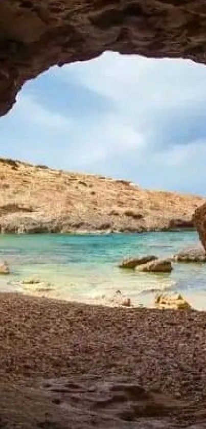 Serene view through a rocky cave opening to a tranquil beach scene.