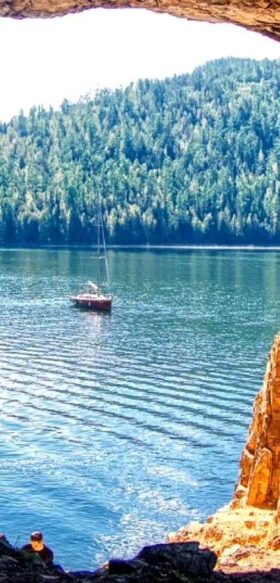 Tranquil lake view through cave with sailboat.