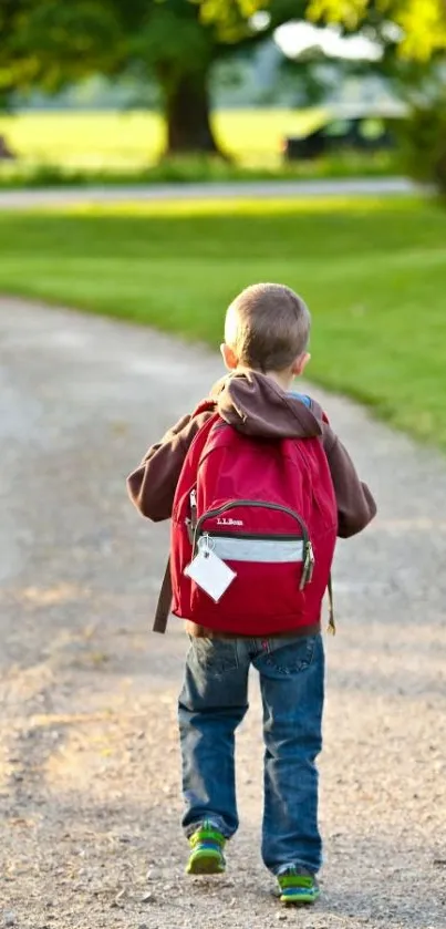 A young boy with a red backpack walking down a peaceful, tree-lined path.