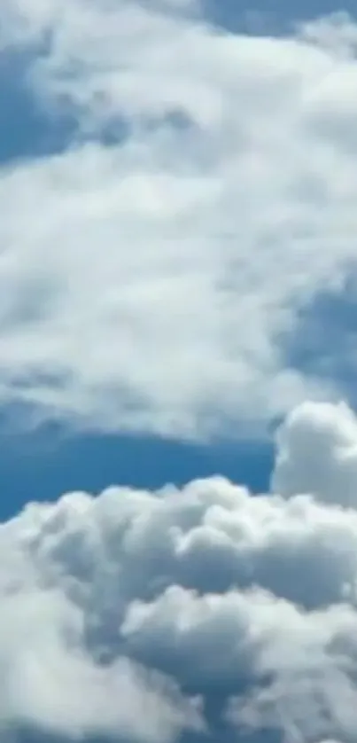 Fluffy white clouds in a clear blue sky wallpaper.