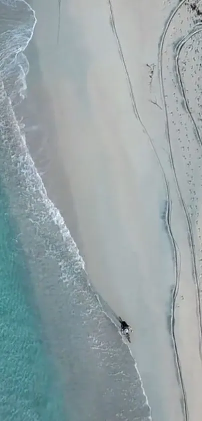 Aerial view of azure waves meeting sandy beach.