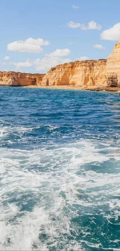 Boat navigating vibrant blue ocean near rocky cliffs under sunny sky.