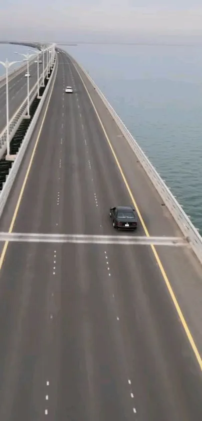 Aerial view of a serene coastal highway with a car driving over calm blue waters.