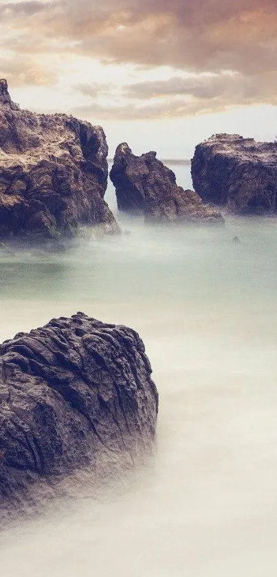 Misty ocean waves crashing against rugged coastal rocks under a cloudy sky.