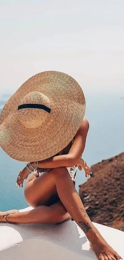 Woman in hat sits by tranquil ocean view.