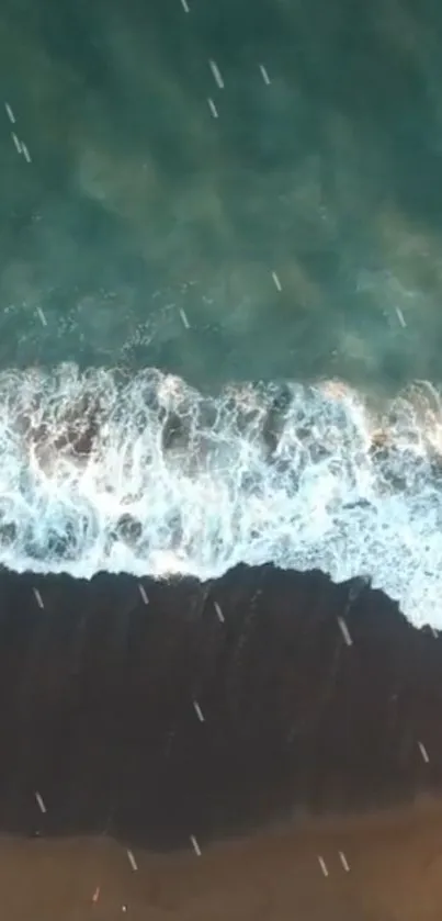 Aerial view of ocean waves crashing onto a sandy shore, creating a serene blue-green scene.