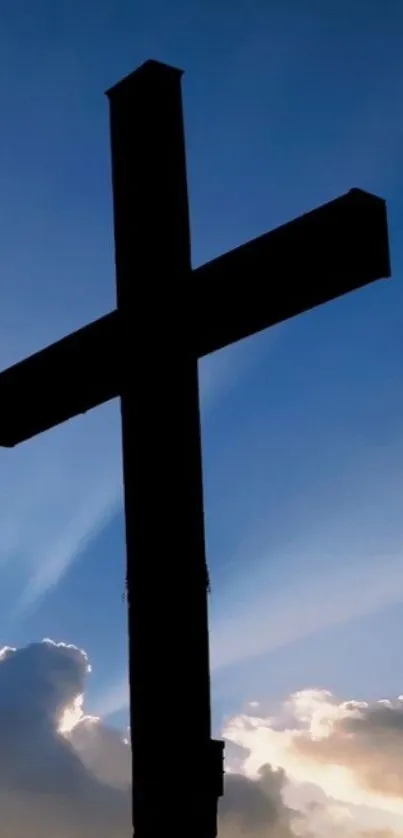 Silhouette of a cross against a vibrant sunset sky with clouds.