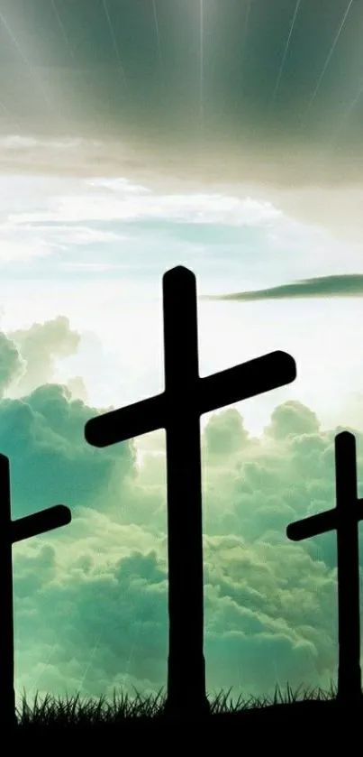 Three silhouetted crosses against a teal sunset sky with clouds.