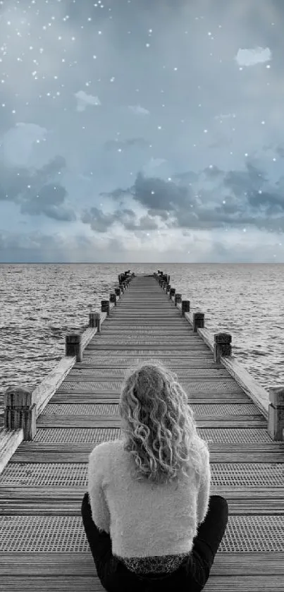 Person sitting on dock facing a dreamy night sky.