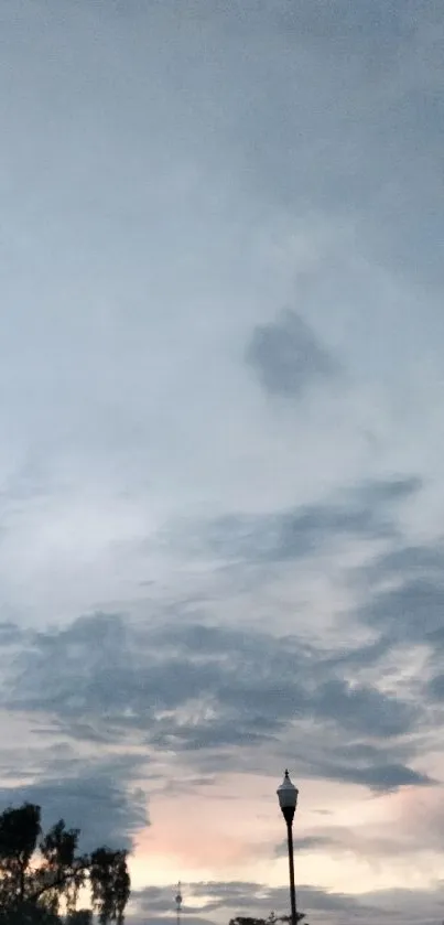 Serene evening sky with clouds and lamp silhouette.