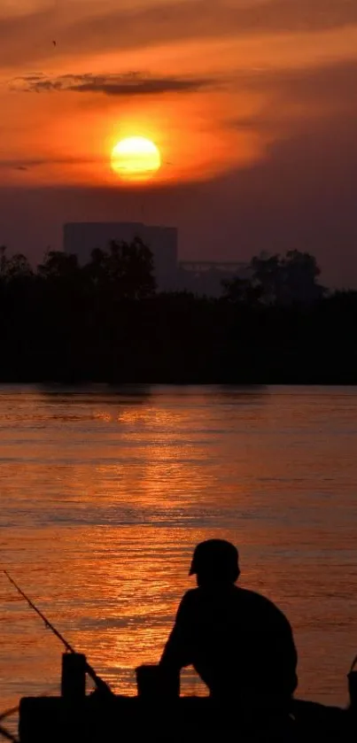 Silhouette of a man fishing during a vivid orange sunset over a tranquil river.