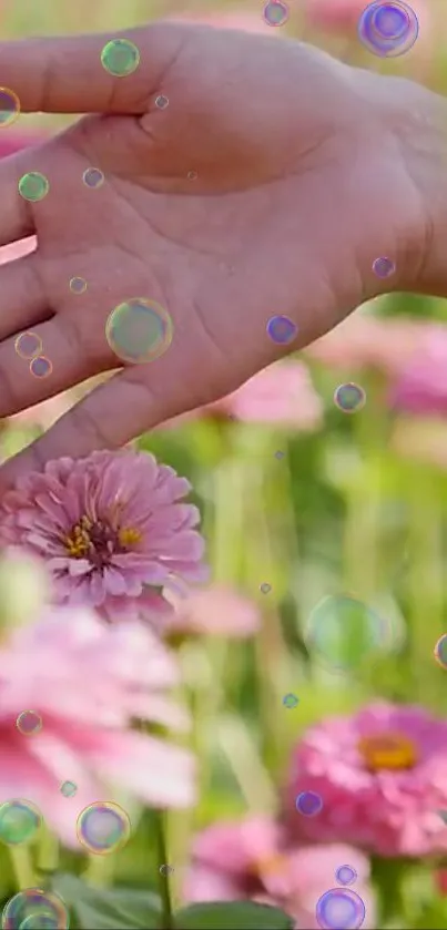 Hand touching pink flowers with bubbles in a serene nature scene.