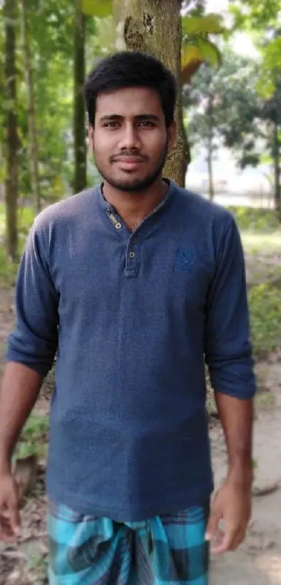 A man stands peacefully in a lush green forest path, exuding serenity.