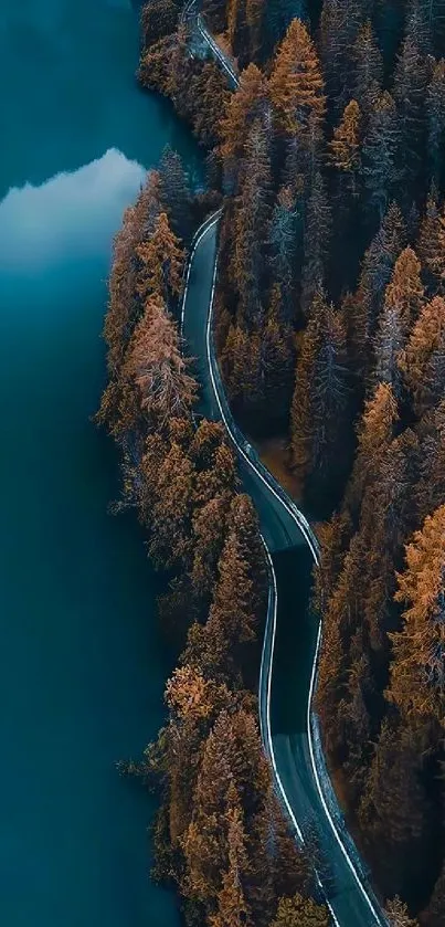 Aerial view of a winding road through autumn trees by a blue lake.