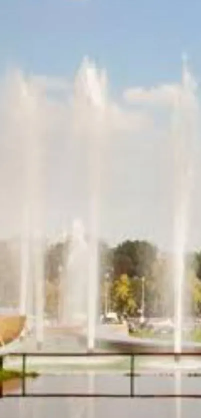 A tranquil park fountain under a bright blue sky with reflections in water.