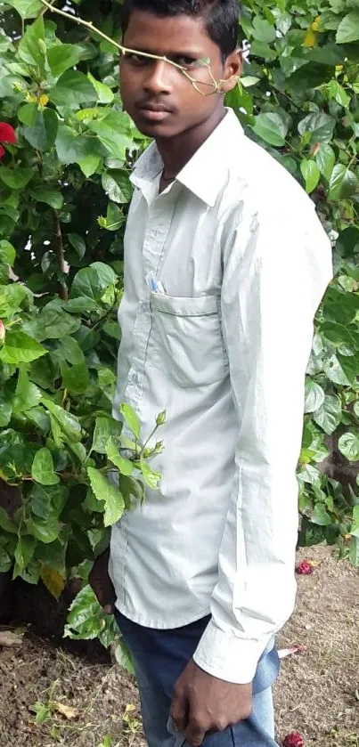 Person in a garden with green foliage and red flowers.