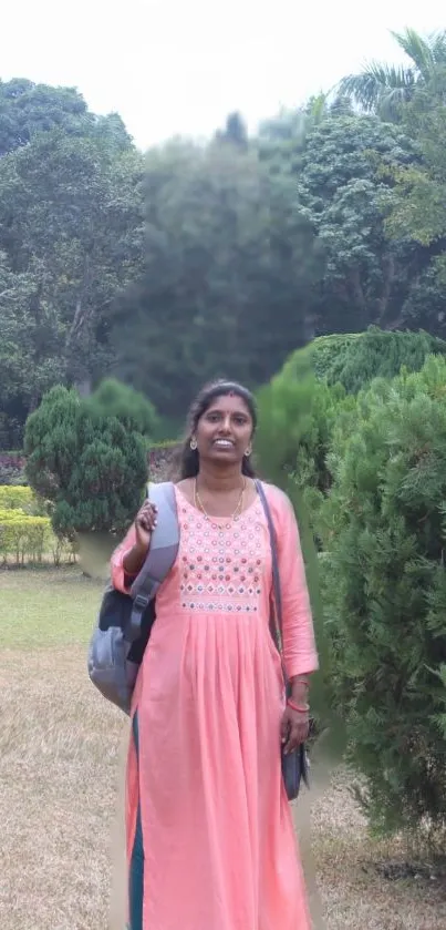 Woman in a pink dress walking through a serene, lush green garden.