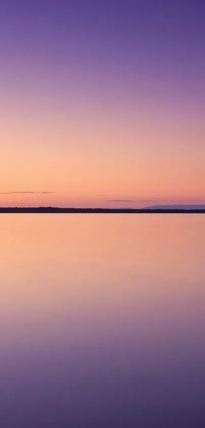 Beautiful tranquil purple and pink gradient over a calm lake at sunset.